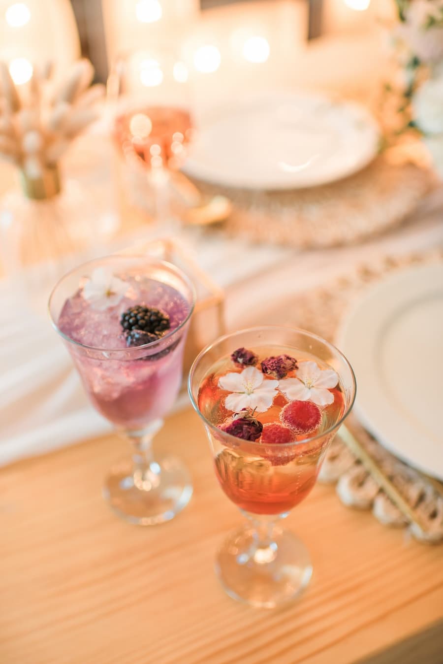 Two elegant botanical signature cocktails with floral garnishes at a wedding reception